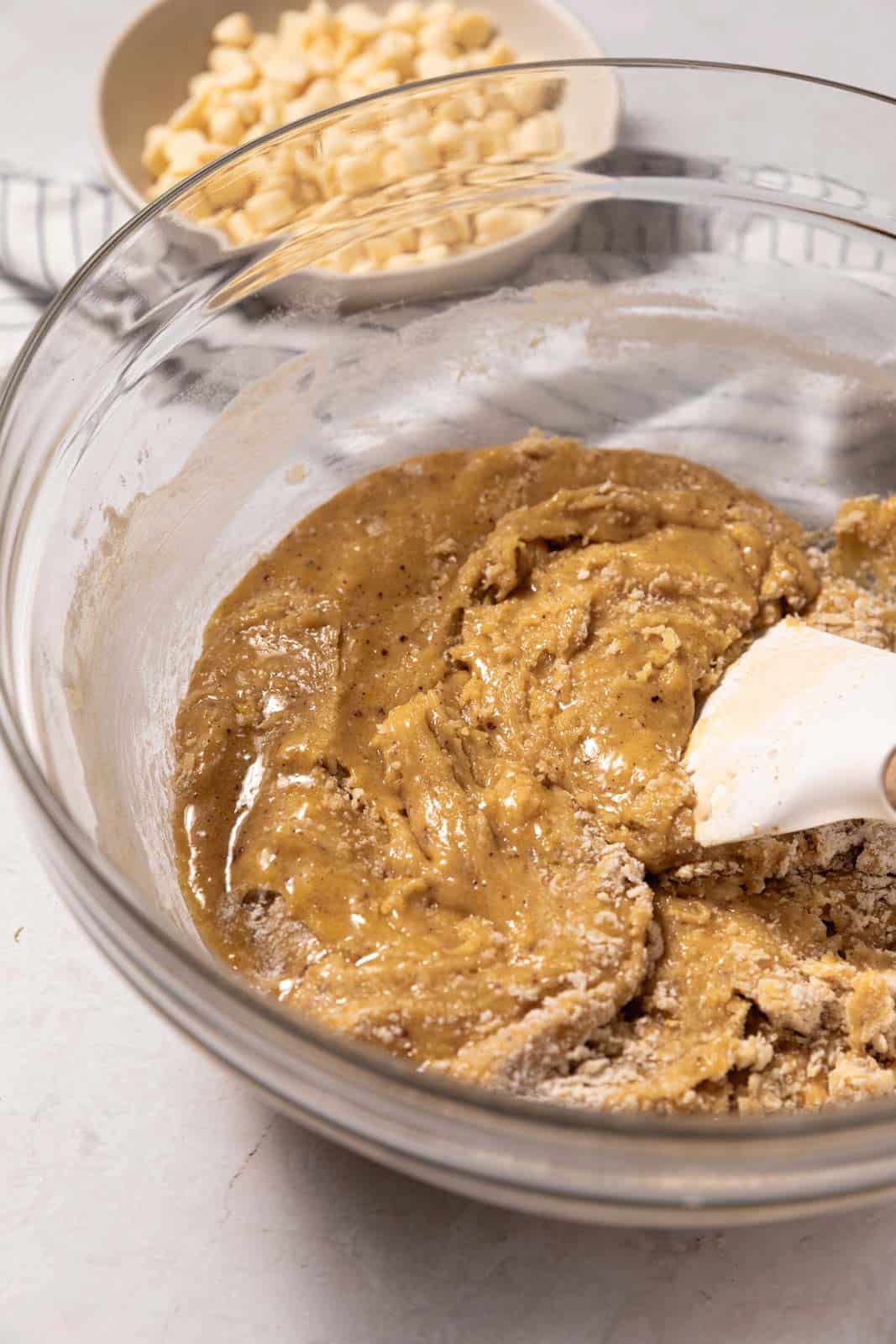 Mixed cookie dough in a glass mixing bowl with a white rubber spatula.
