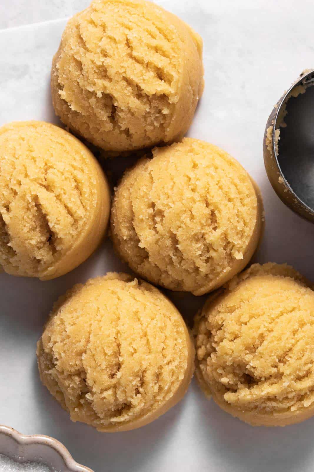 Over head shot of five sugar cookie dough balls on a flat white surface.