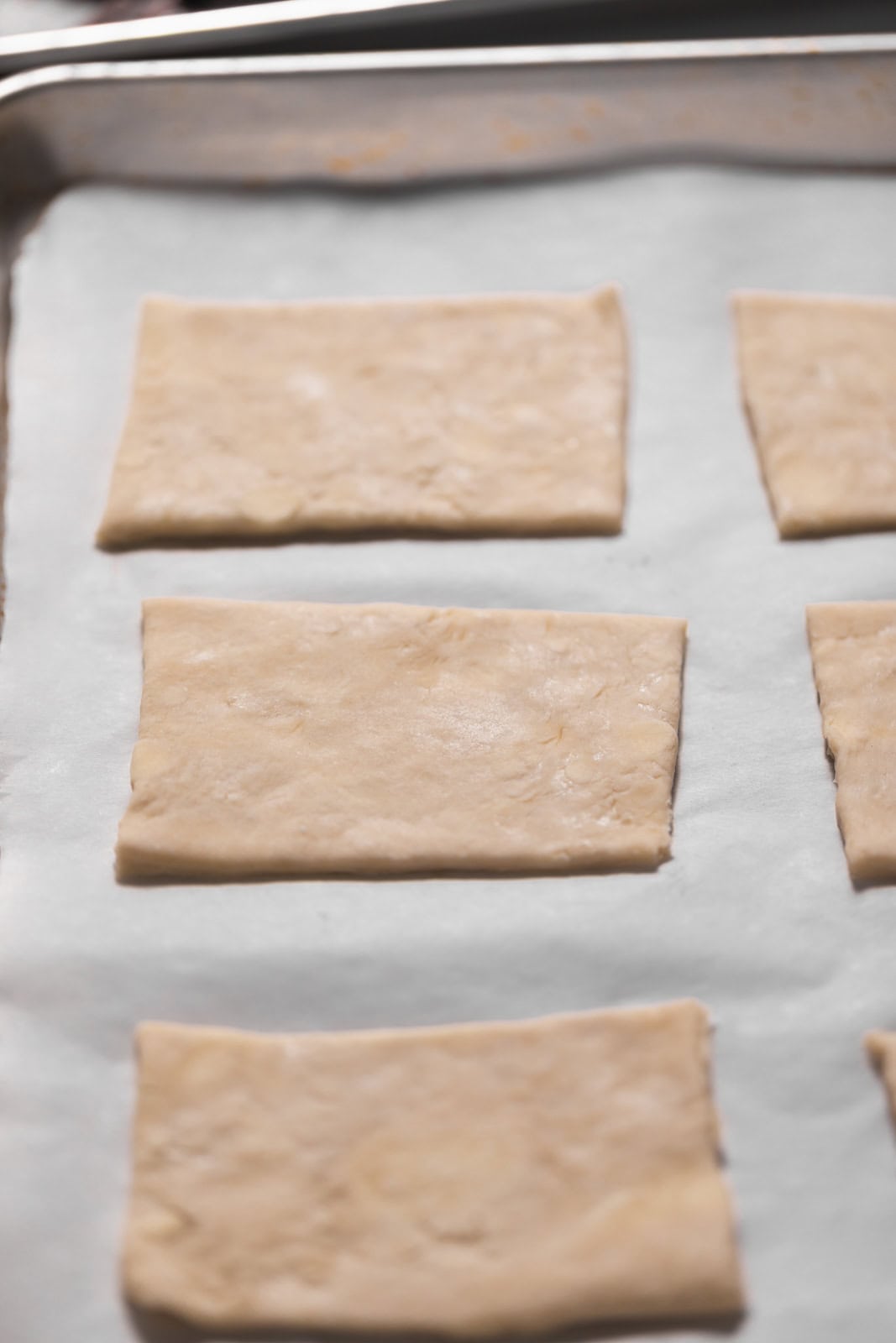 Pie dough cut into rectangles for hand pies set on a parchment lined sheet pan.