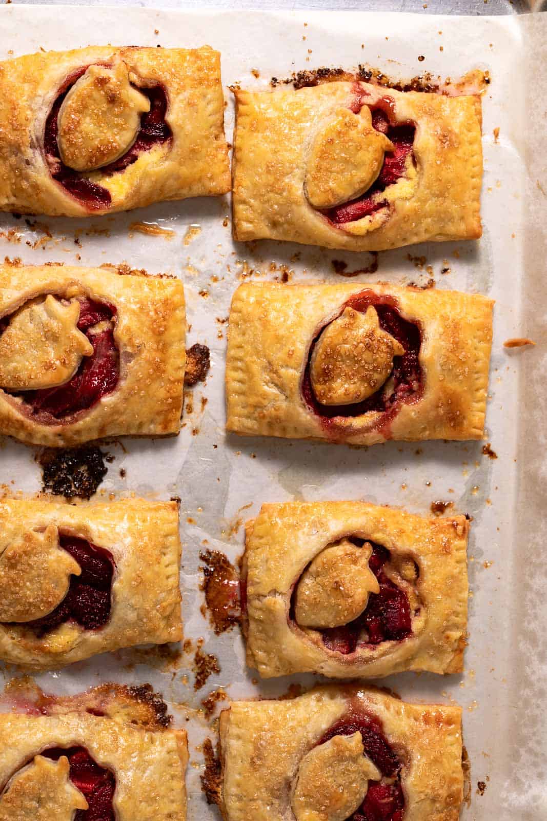 Roasted strawberry hand pies on a parchment lined sheet pan.