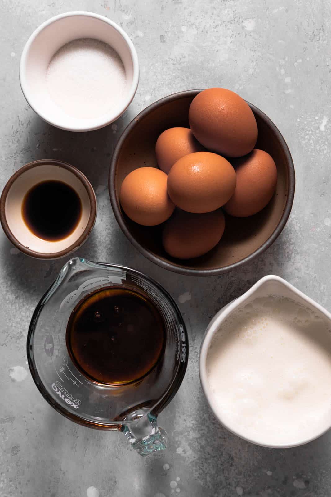 Ingredients for maple creme brulee in cups set on a flat surface.