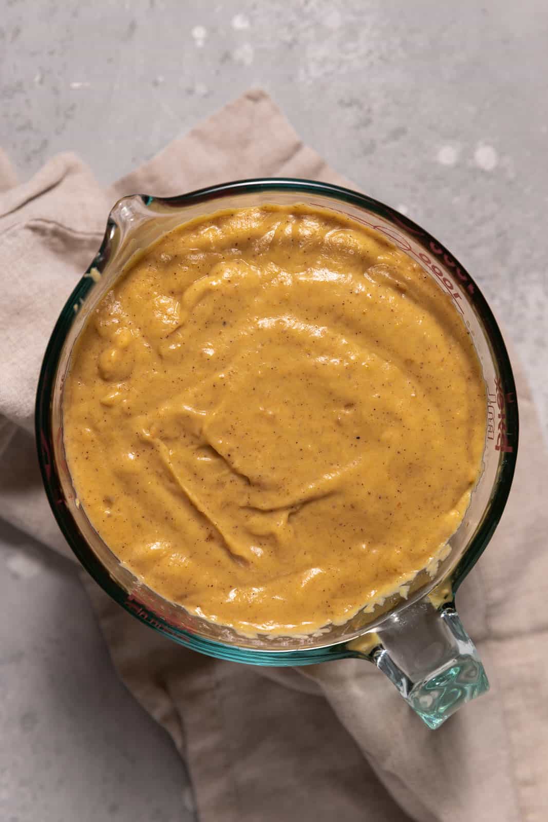 Overhead shot of Pumpkin custard in a large glass pour measuring cup set on a linen.