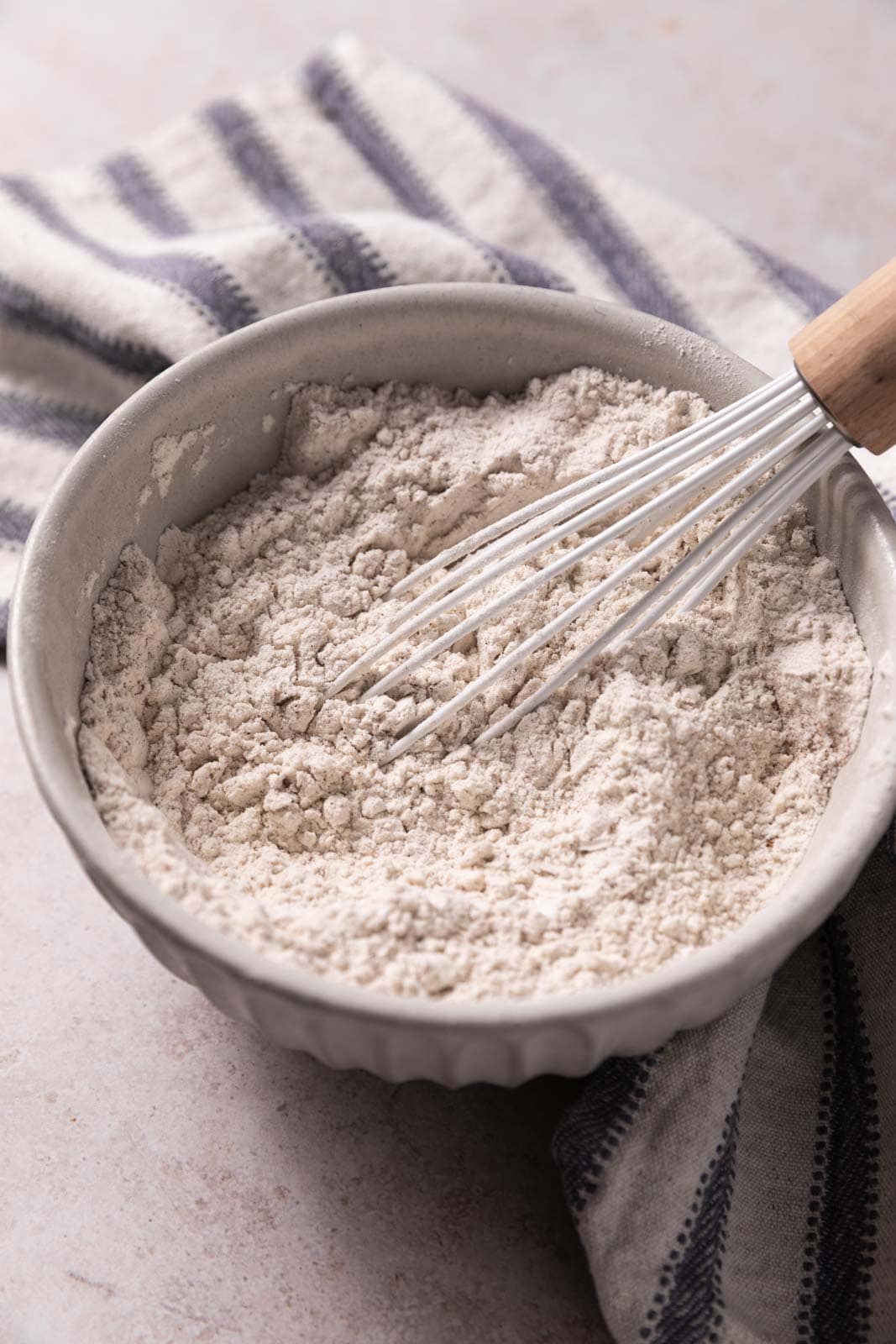 Whisked dry ingredients in a ceramic bowl with a white wire whisk.