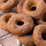 Close up of baked pumpkin donuts stacked on a round wire cooling rack.