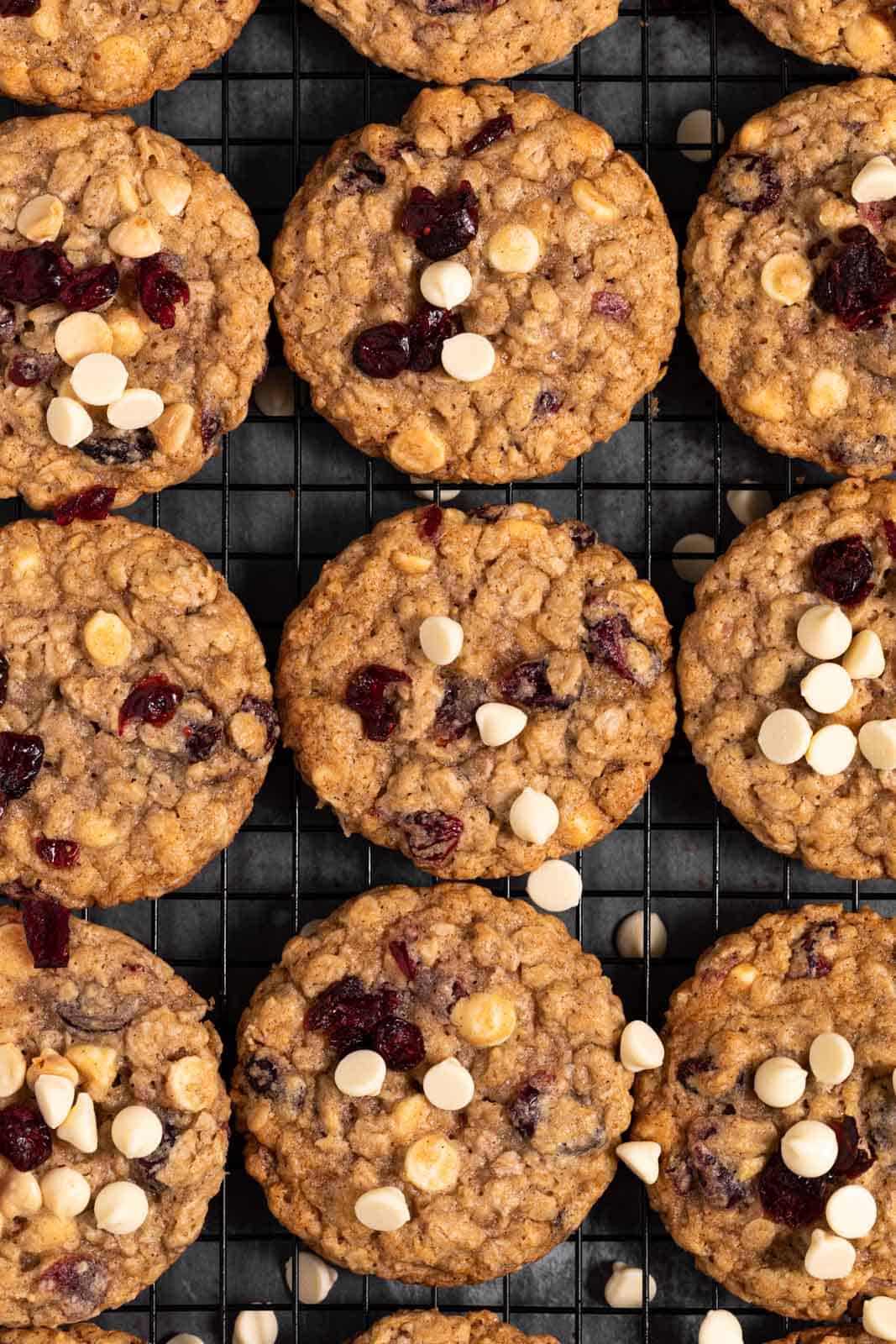 White chocolate cranberry oatmeal cookies in a single layer on a black wire cooling rack.