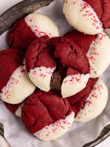 Red velvet cookies dipped in white chocolate and arranged in a parchment lined metal pie tin.