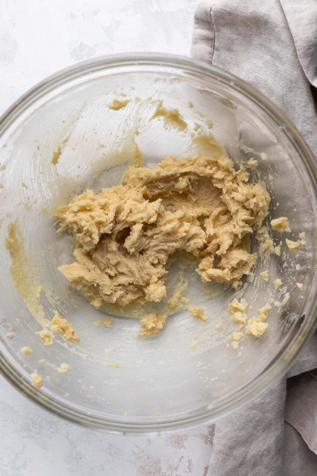 Creamed butter and sugar in a glass mixing bowl set of a flat surface.