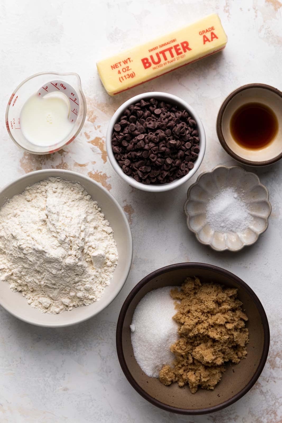 Ingredients for edible chocolate chip cookie dough in bowls set on a flat surface.