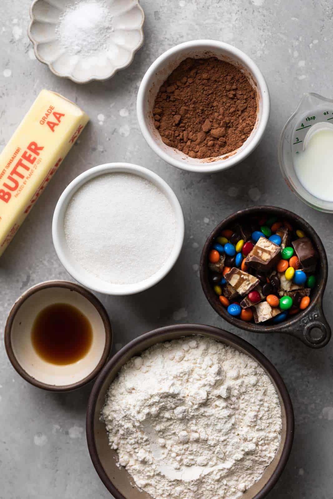 Ingredients for edible chocolate cookie dough in bowls on a flat grey surface.