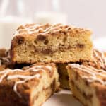Close up sour cream coffee cake with a slice stacked on top all set on white parchment paper set on a round wire rack.