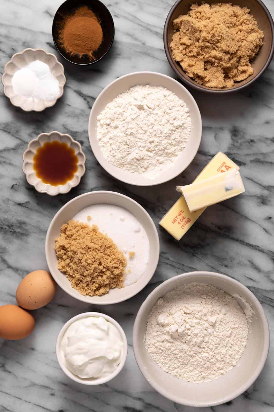 Overhead shot of sour cream coffee cake ingredients in bowls set on a marble surface.