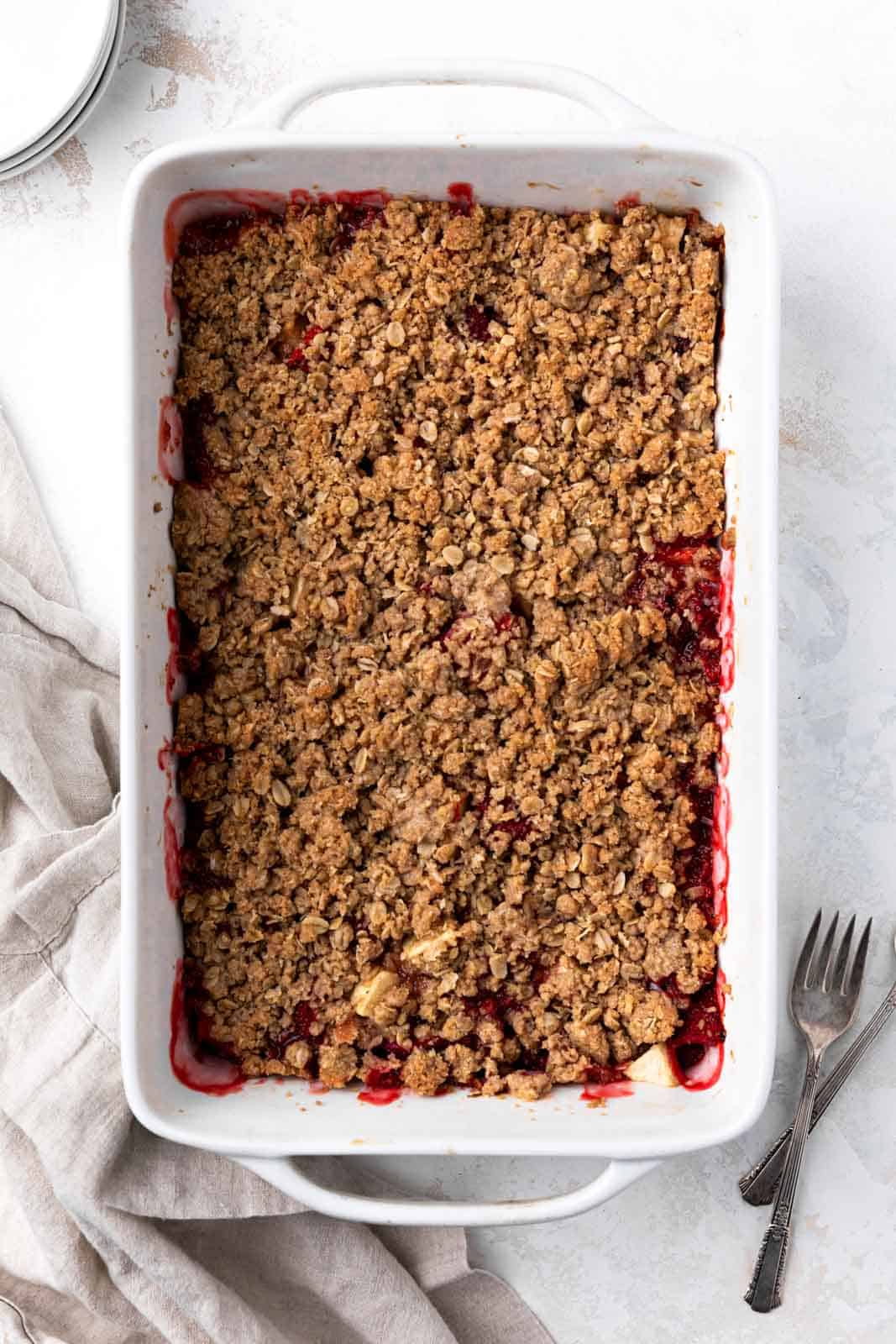 Crisp topping on a strawberry apple crisp in a white ceramic rectangular baking dish on a flat surface.