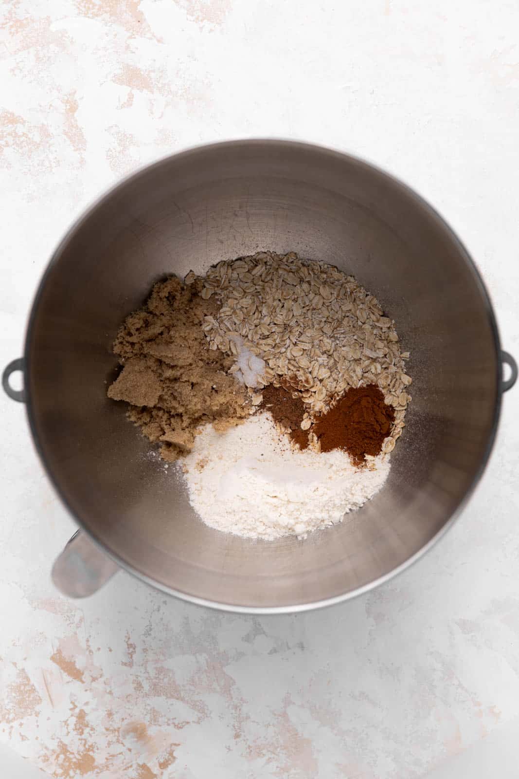 Dry ingredients for crisp topping in a metal stand mixer mixing bowl set on a flat surface.