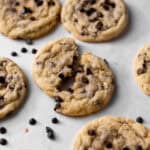 Chocolate chip sugar sugar cookies with mini chocolate chips arranged on a white parchment paper with one broken in half.