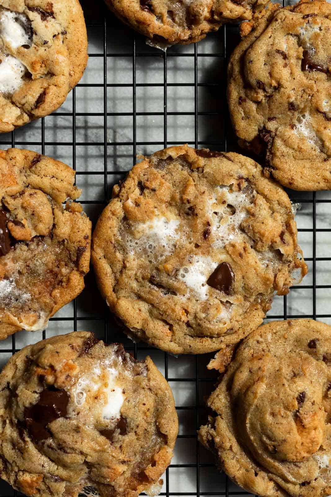 Brown butter s'mores cookies arranged flat on a black cooling rack.