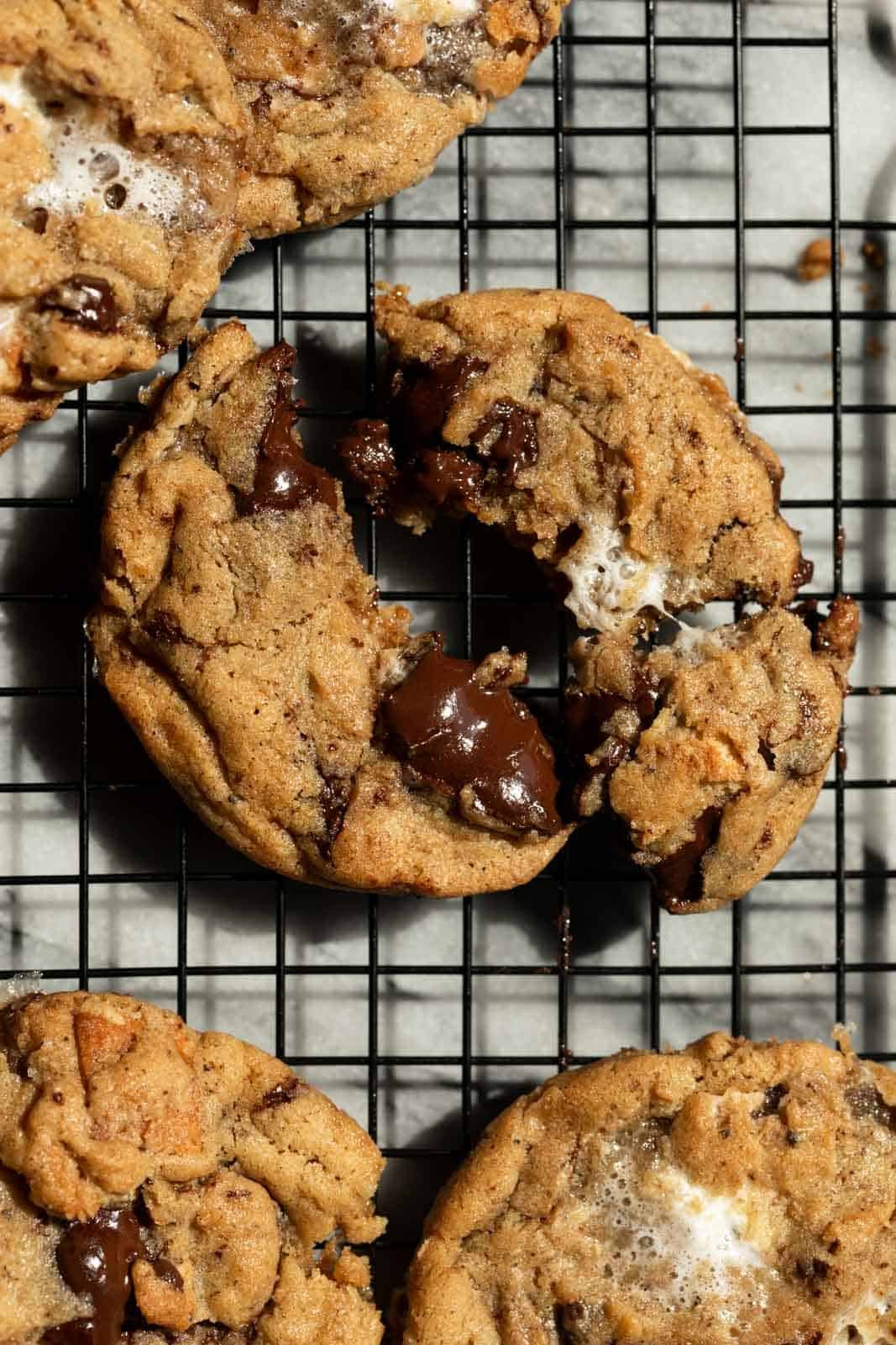 Close up of brown butter s'mores cookie broken in half with gooey chocolate showing.
