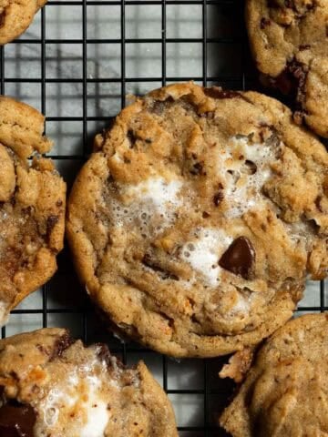 Brown butter s'mores cookies arranged flat on a black cooling rack.