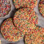 Sprinkle sugar cookies arranged on a marble slab.