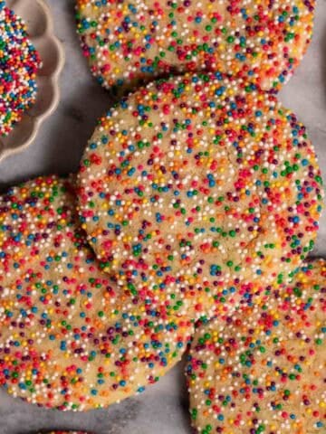 Sprinkle sugar cookies arranged on a marble slab.
