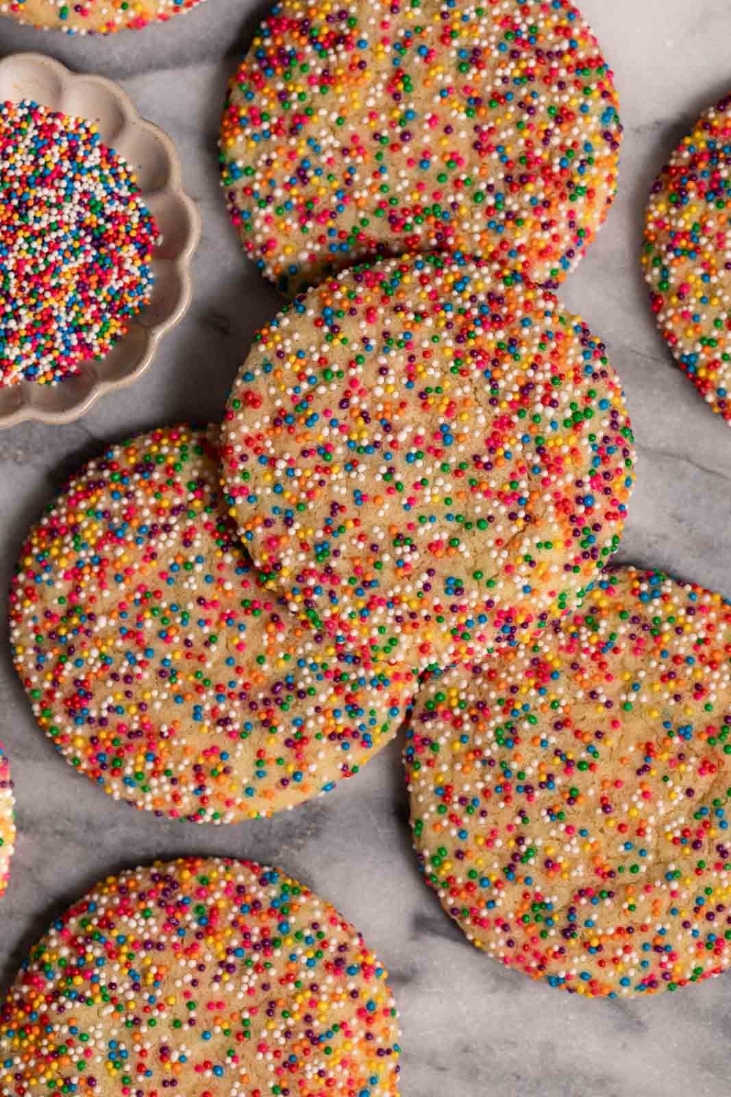 Sprinkle sugar cookies arranged on a marble slab.