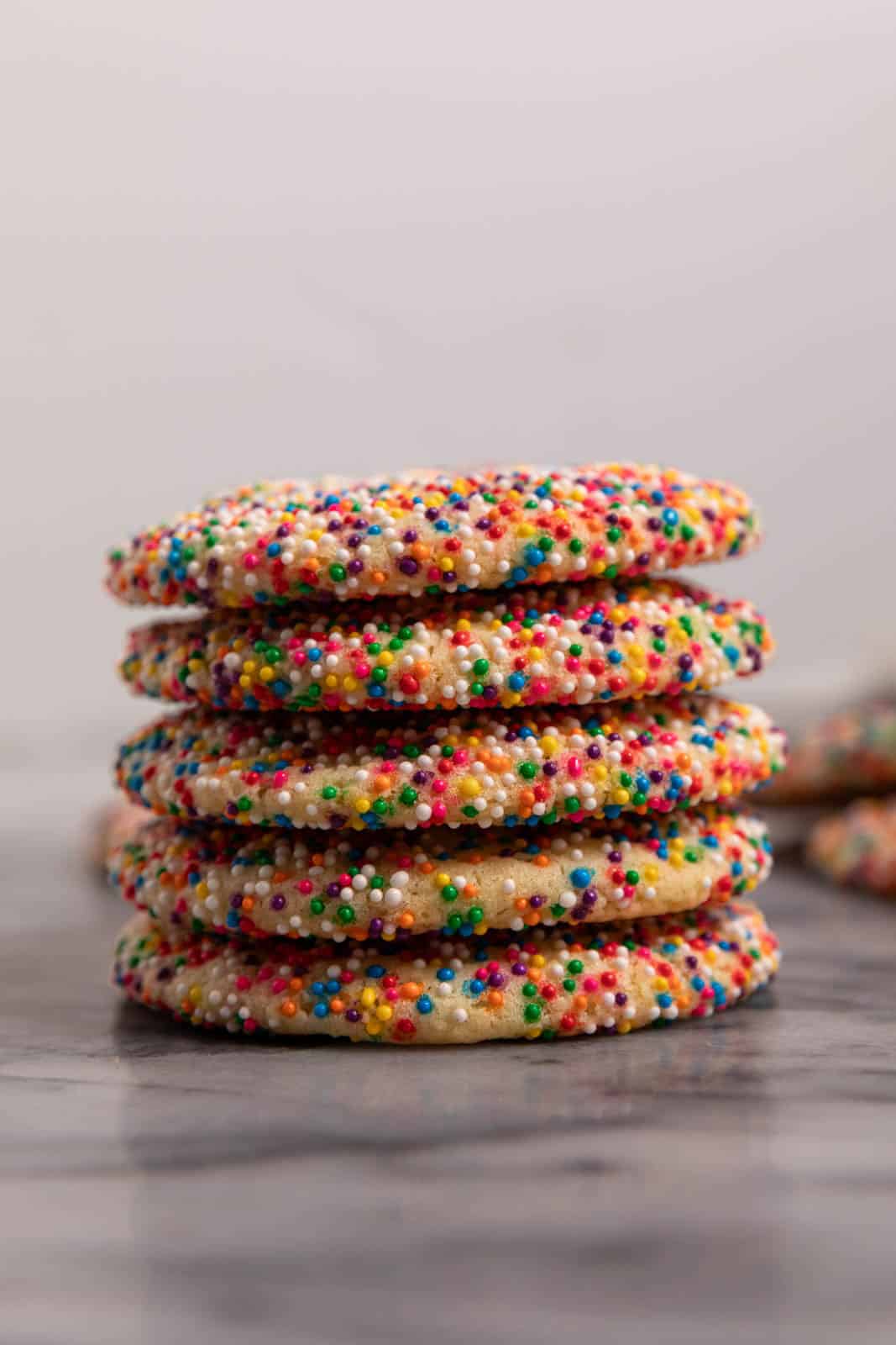 Stack of sprinkle sugar cookies on a marble slab.
